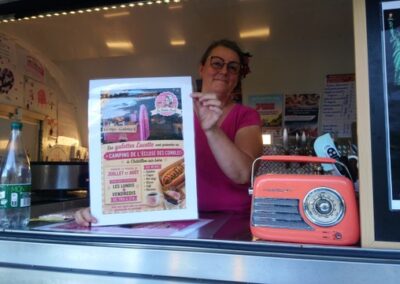 La crépière présente la carte des galettes depuis son camion