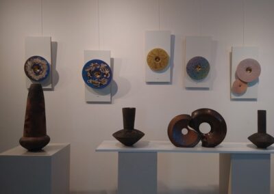 Des vases et des pièces circulaires en céramique exposés sur des socles