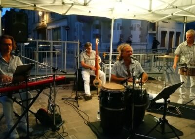 Trois musiciens donnent un concert sous un chapiteau éclairé
