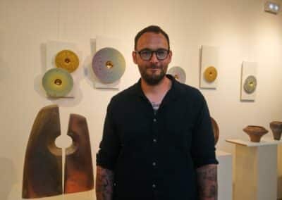 Le céramiste devant ses œuvres présentées à l’espace culturel