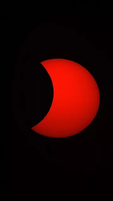 Disque rouge du Soleil partiellement masqué par la Lune, photographié à Gien avec un Seestar S50